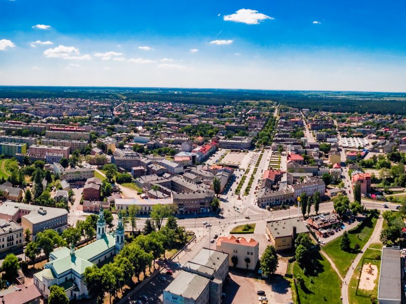 Na zdjęciu panorama Tomaszowa Mazowieckiego z lotu ptaka. Widać z wysokości budynki, ulice i zieleńce